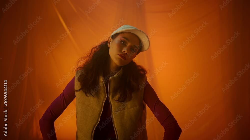 Stylish model posing elegantly in a trendy outfit against a bright orange background