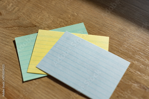 Three different colored index cards on a wooden desk. Office utensils; business; workplace; office stuff. photo