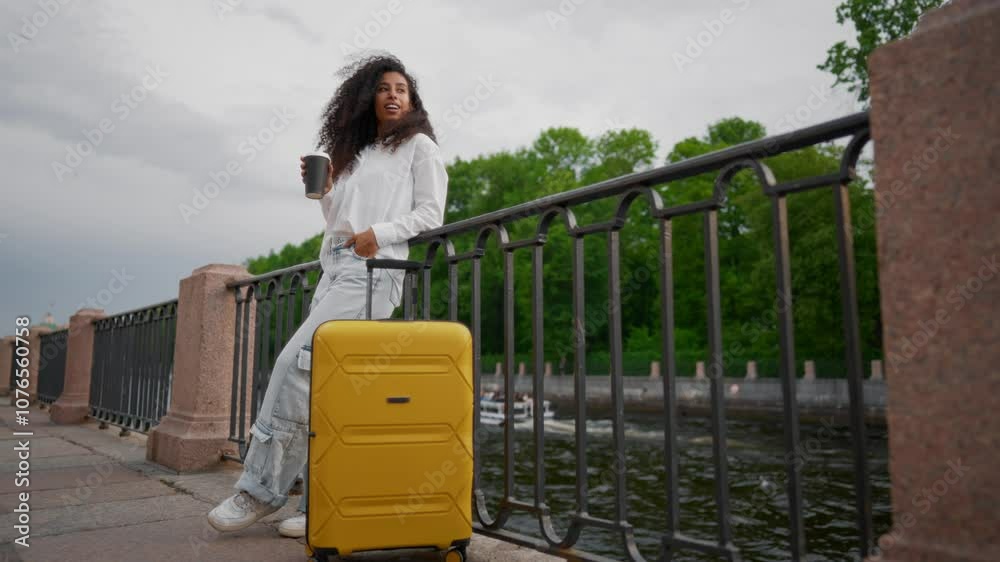 Carefree biracial young woman standing alone on embankment, drinking coffee. Portrait of female tourist or travel blogger visiting beautiful city, full-length shot, summer vacation or business trip