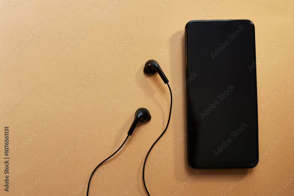 Earphones, mockup space and phone on table for streaming music, podcast or radio online. Audio tech, cellphone and top view of screen for playing song, playlist or album on mobile app by desk.