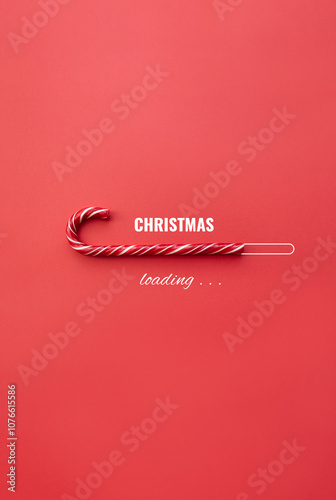 Striped candy cane and lettering Christmas loading on red background. Concept of waiting for seasonal holidays. Vertical banner for social media. Copy space, selective focus photo