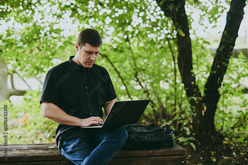 Portrait of young freelance programmer man working with laptop in forest park, software developer, IT technologies Portrait of young freelance programmer man working with laptop in forest park, software developer, IT technologies