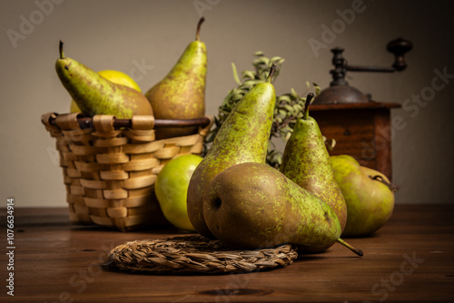 Close-up of pears, basket and mill on wooden table, dark background, horizontal with copy space