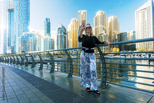 Photography A woman takes a selfie in front of the Dubai Marina on a sunny autumn day in Dubai, UAE