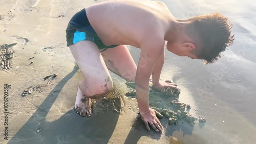 a boy sculpts from wet sand on the seashore