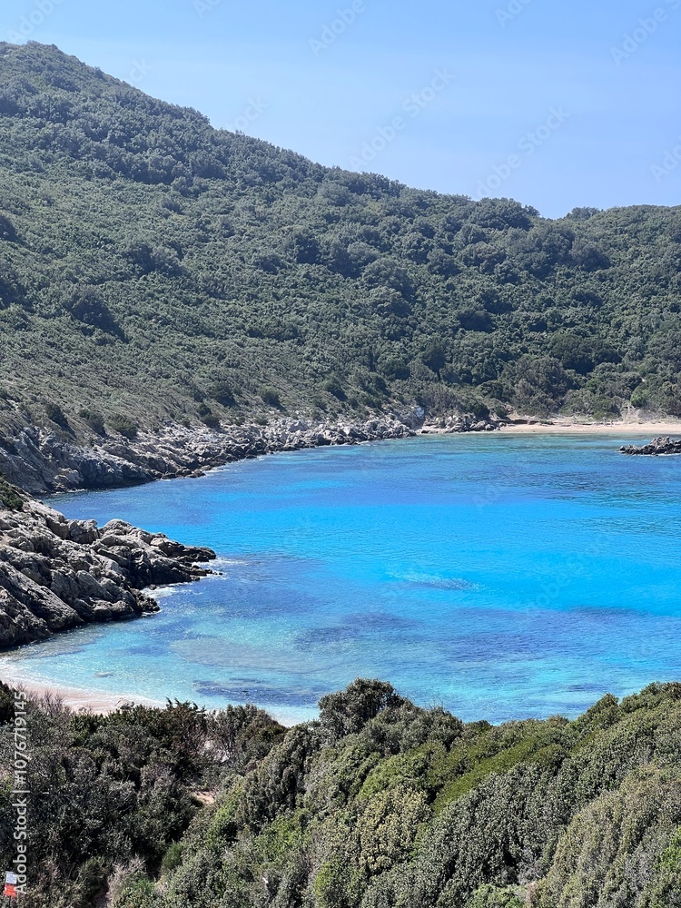 Fototapeta premium Beautiful summer panoramic seascape in Porto Timoni on the Greek island of Corfu. View from the rocky cliff to the crystal clear and azure sea bay and distant islands. A unique secluded beach. 