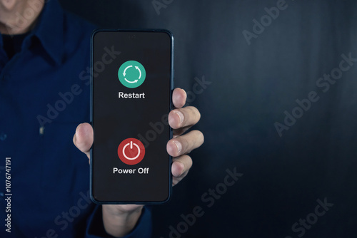 Man holding a smartphone with power off and restart icon on the screen. photo