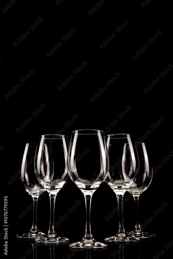 Set of five empty wine glasses perfectly arranged with reflections on a black background. Suitable for celebration, elegance or haute cuisine themes. Set of five empty wine glasses perfectly arranged with reflections on a black background. Suitable for celebration, elegance or haute cuisine themes.