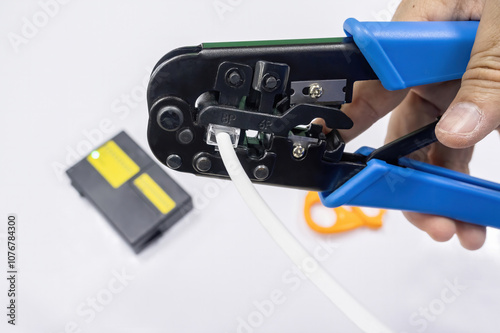 An IT network engineer using a crimping tool to attach an RJ45 connector to a network cable.