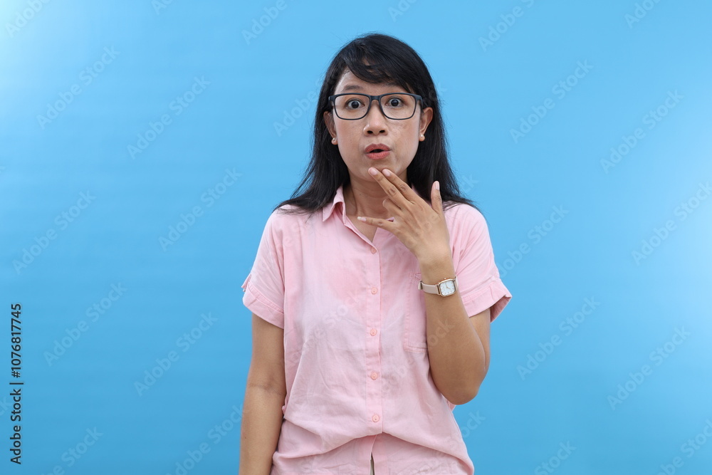 Confused shocked Asian woman reacts on something with wondered frightened expression wears casual shirt looks startled stares at promo logo isolated over blue wall Confused shocked Asian woman reacts on something with wondered frightened expression wears casual shirt looks startled stares at promo logo isolated over blue wall