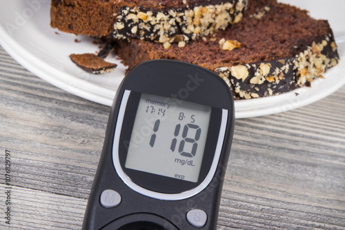 Glucose meter with high result sugar level, sweet chocolate cake. Nutrition during diabetes