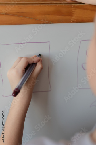 A preschool-age boy, left-handed, writes on a blackboard. preparing for school. logical tasks. homeschooling