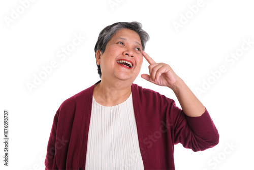 Fotografie Joyful senior woman pointing to her head with a smile, expressing a moment of realization or inspiration