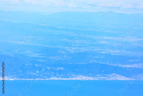 Flying above a tranquil sea and blue mountains
