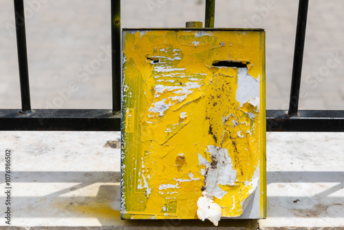 Yellow, aged, tzedakah box for collecting coins for charity, mounted to an iron fence in a religious neighborhood of Jerusalem, Israel. photo