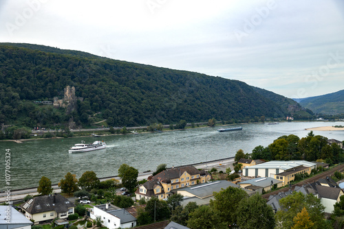 Assmanshausen, view on the Rhine with a tourist and transport ship, castle in the forest in the background. Travel destination, beautiful Rheingau region in Germany.