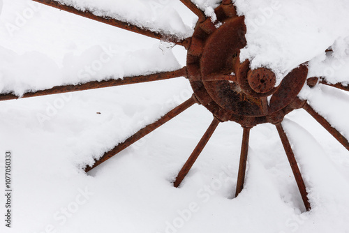 Fotografie The rusty spokes and center of an old farm hay rake wheel is covered from a December snowfall within the Pike Lake Unit, Kettle Moraine State Forest, Hartford, Wisconsin