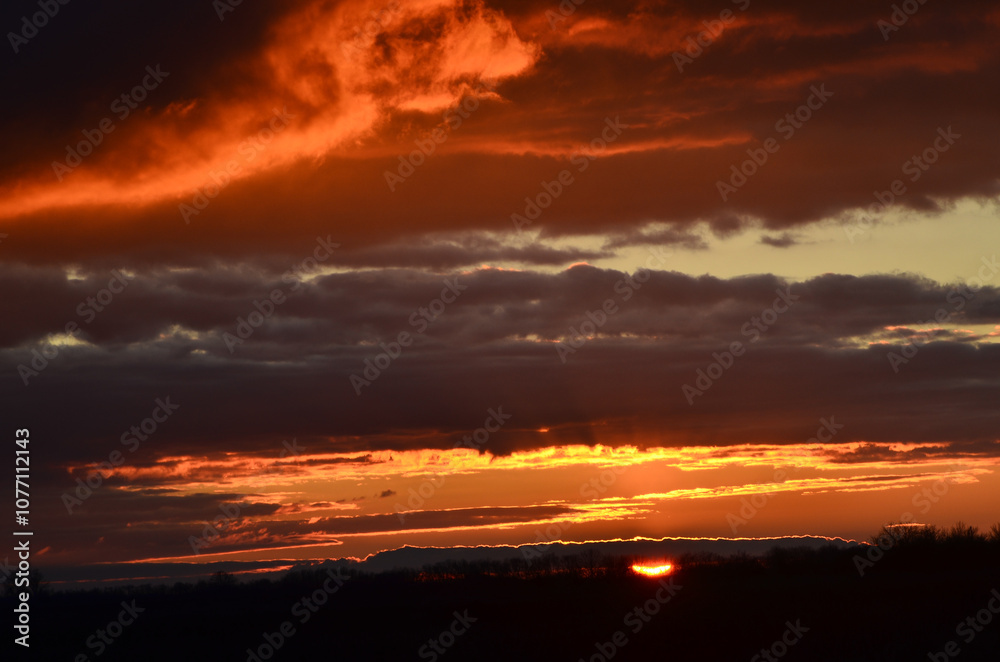 Fototapeta premium Sunset, golden, orange, red clouds, against the dark sky.