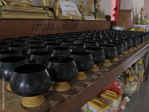 Monks' alms bowls are arranged in a Thai temple.