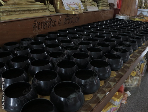 Monks' alms bowls are arranged in a Thai temple.