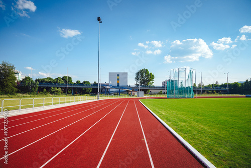 View of a Modern Athletic Stadium with 8-Lane Red Track, Nestled in Vibrant Green Fields and Surrounded by Serene Natural Landscape