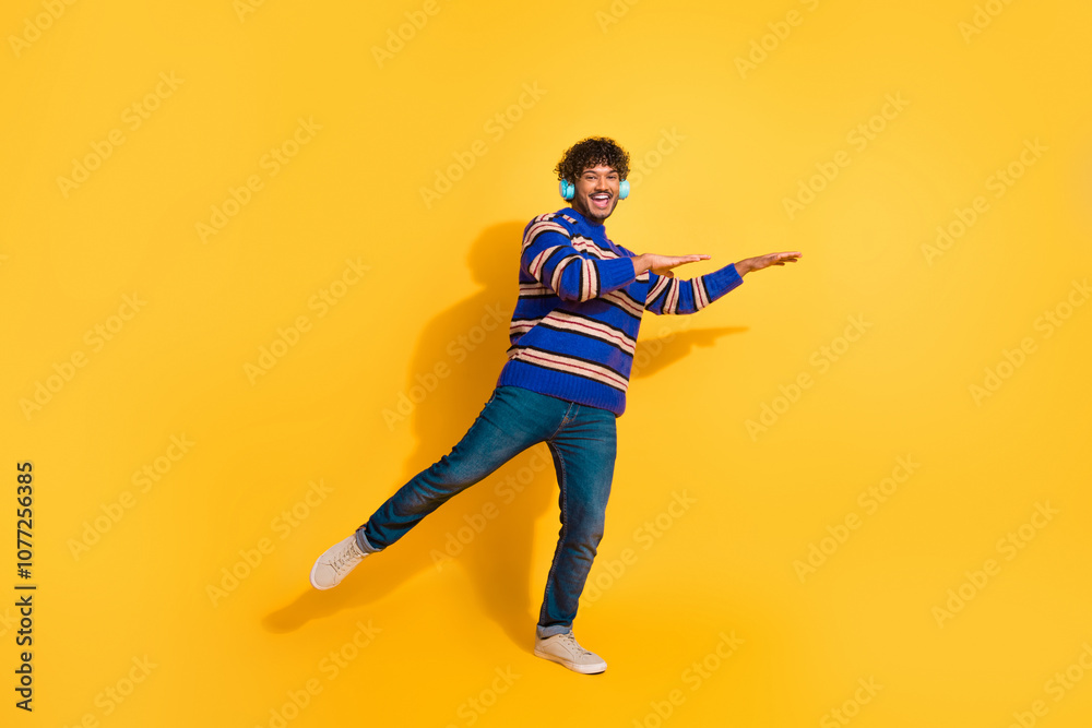 Fototapeta premium Full size photo of pretty young male headphones dancing wear stylish blue striped outfit isolated on yellow color background