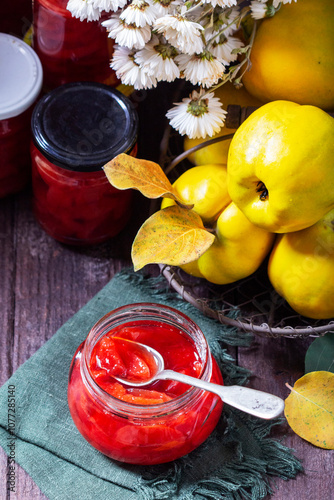 Quince jam in a glass jar, quince in a basket and a bouquet of chrysanthemums. Autumn still life.