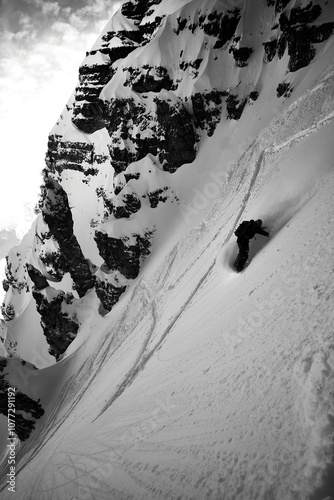 Snowboarder carving through powder on a steep mountain slope in a remote winter landscape