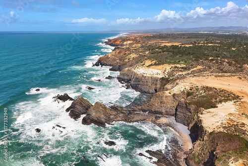 Aerial view of the steep cliffs and ocean waves crashing into the shore. Fishermen's Trail, Portugal
