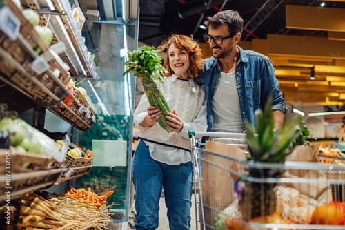 Happy couple choosing fresh produce while grocery shopping at supermarket