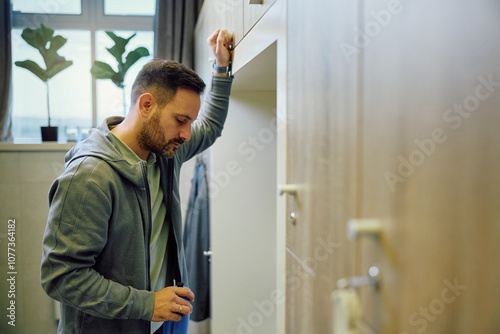 Pensive athletic man on water break at gym's dressing room. Copy space.