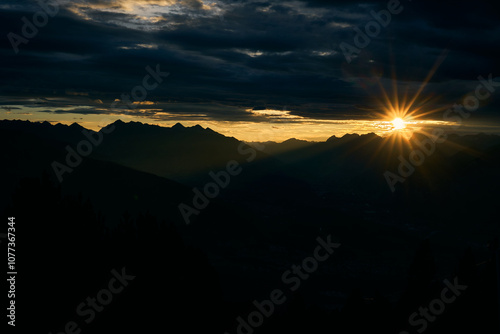 Majestic sunrise over mountain peaks illuminates the sky and casts shadows in the valley below at dawn