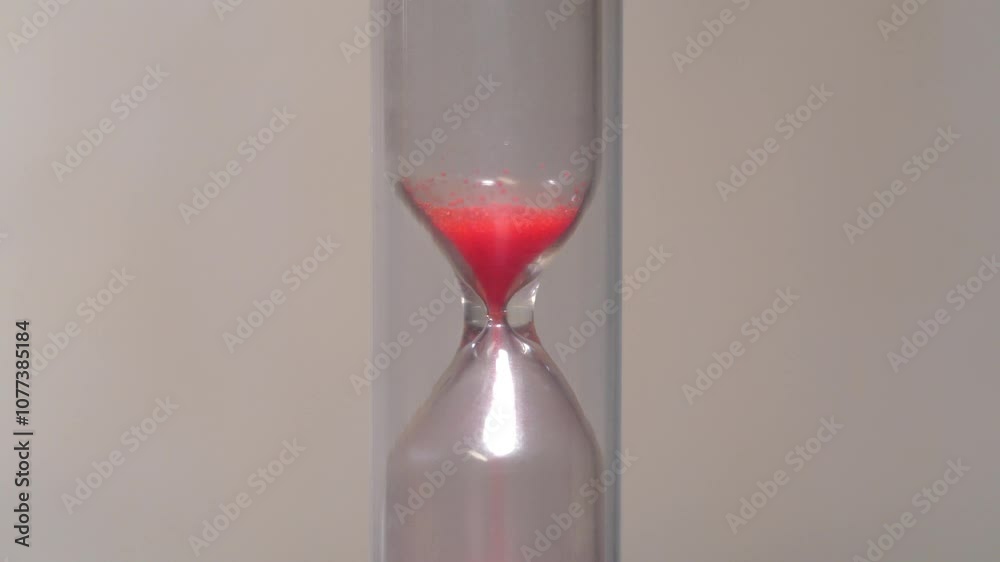 Red sand in hourglass. Time flows backwards, in the opposite direction. Time is like sand in the endless desert, but remember, your handful is in the hourglass. 4K 60fps macro shot reverse time video