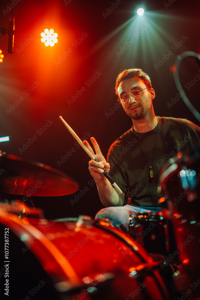 Fototapeta premium Drummer performing live on stage with red backlights