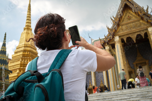 Tourist taking pictures of wat phra kaew in bangkok, thailand