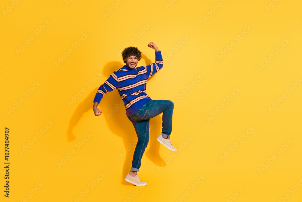 Fototapeta premium Full size photo of pretty young male winning celebrate raise fists wear trendy blue striped outfit isolated on yellow color background