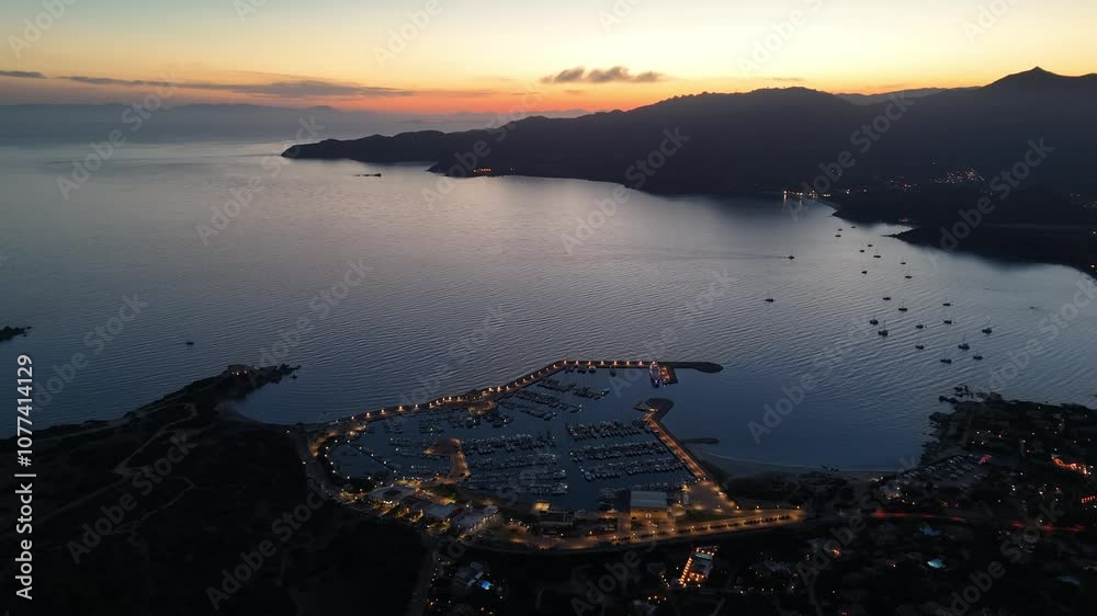 Stunning sunset over Sardinia's tranquil harbor showcases serene waters and distant mountains Stunning sunset over Sardinia's tranquil harbor showcases serene waters and distant mountains