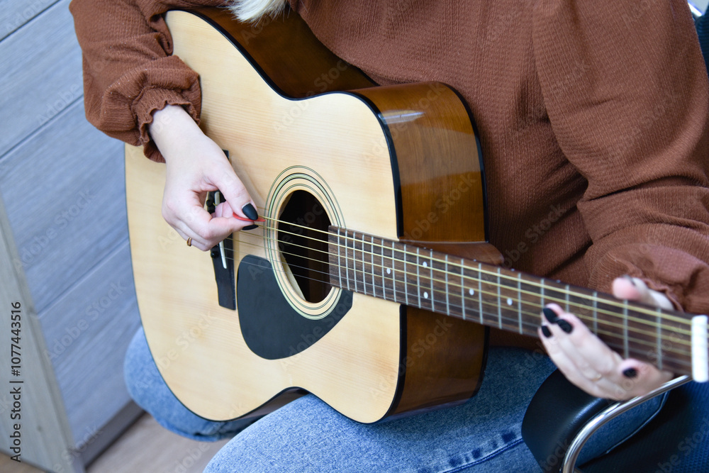 Fototapeta premium Female hands on the guitar. Close-up guitar fragment
