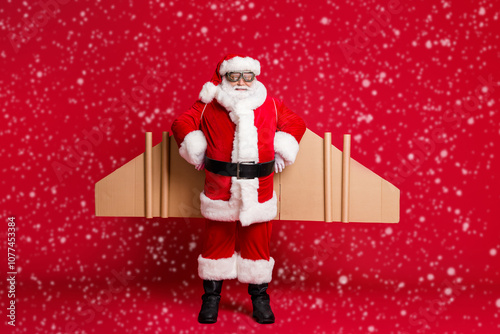 Full body size photo of retired grandpa white beard jetpack ready start long flight north pole trip wear santa x-mas costume coat spectacles headwear isolated red color background photo