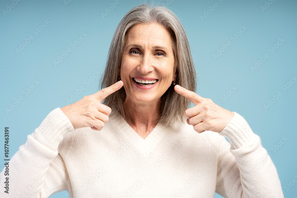 Portrait of smiling, beautiful senior woman pointing fingers on teeth smile, looing at camera Portrait of smiling, beautiful senior woman pointing fingers on teeth smile, looing at camera