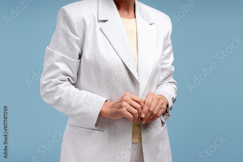 Closeup, senior woman wearing casual, stylish suit, fashion model posing isolated on blue background