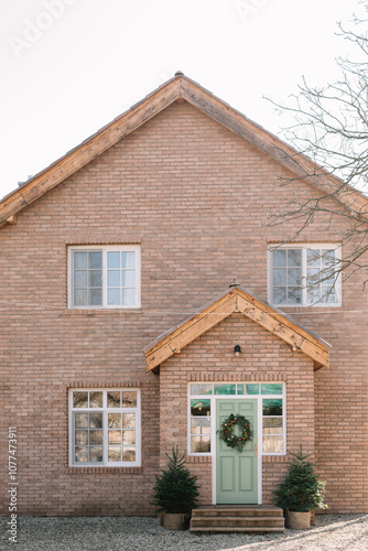 Charming brick house with green door and wreath decor photo