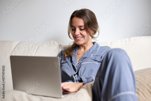 happy woman texting with friends on laptop at home in pajamas photo