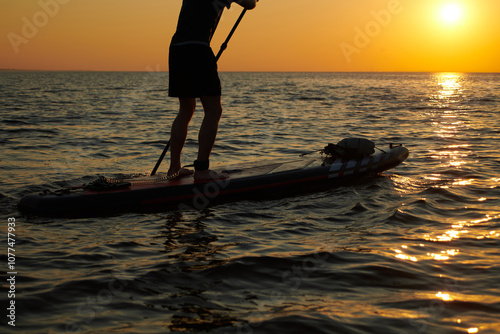 Paddleboarding at sunset over calm water in the evening glow