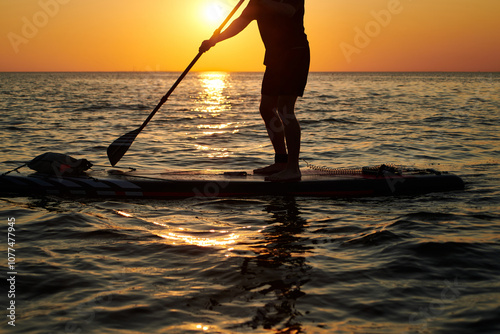 Paddleboarding at sunset over calm water in the evening glow