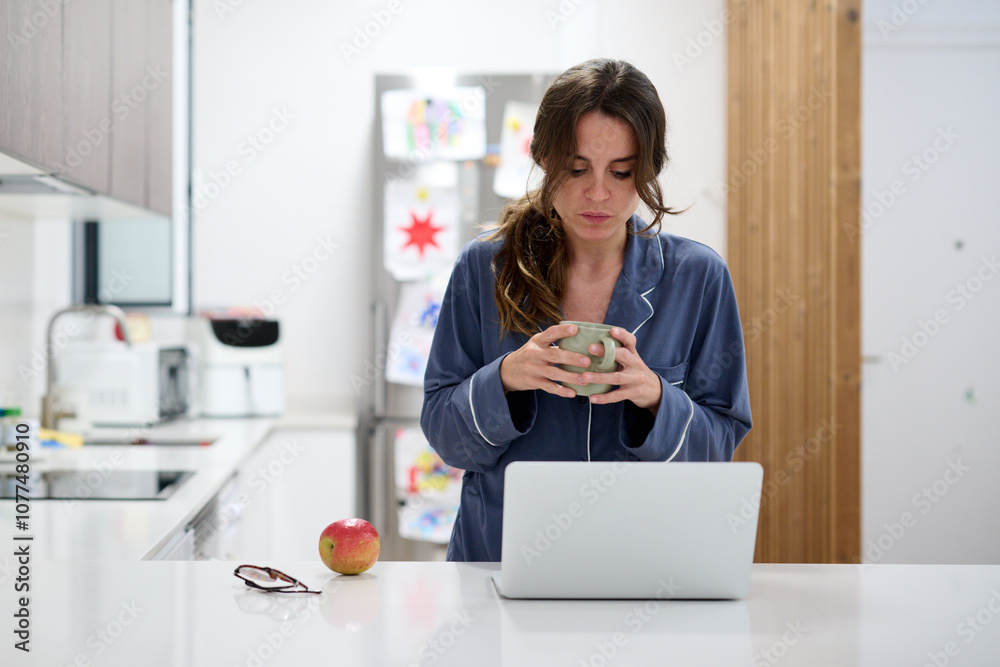 Woman enjoying coffee in a kitchen with a laptop Woman enjoying coffee in a kitchen with a laptop