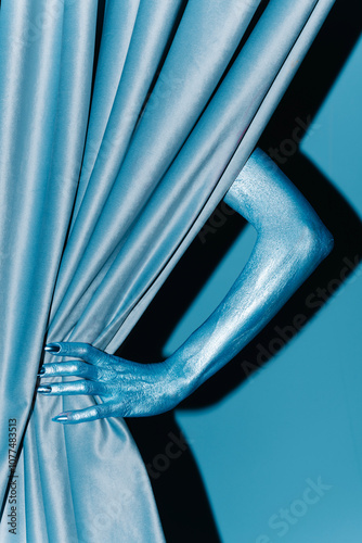 Metallic Hand Pulling Back Blue Curtain in Bold Conceptual Art photo