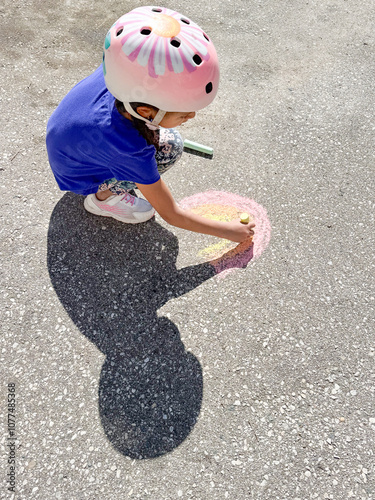 Child drawing a beautiful rainbow in chalk on the driveway pavement