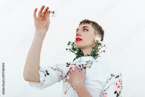 Dreamy non binary person looking at flower photo