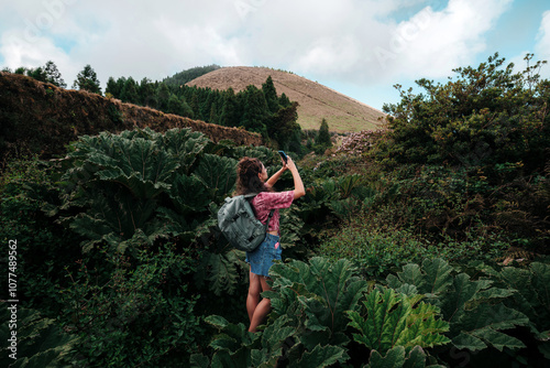 Tourist in nature taking pictures with her phone